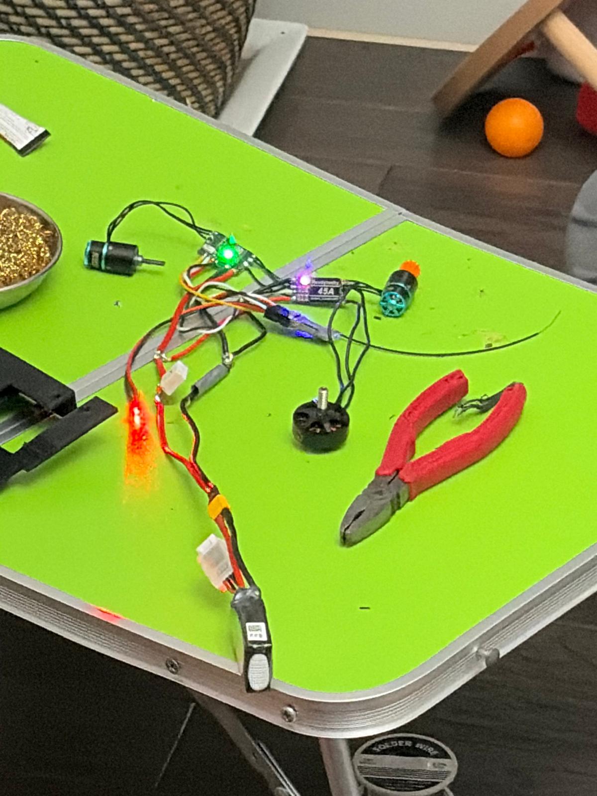 the powered harness with the esc leds lit and a red glow, the 2305 weapon motor and cutters